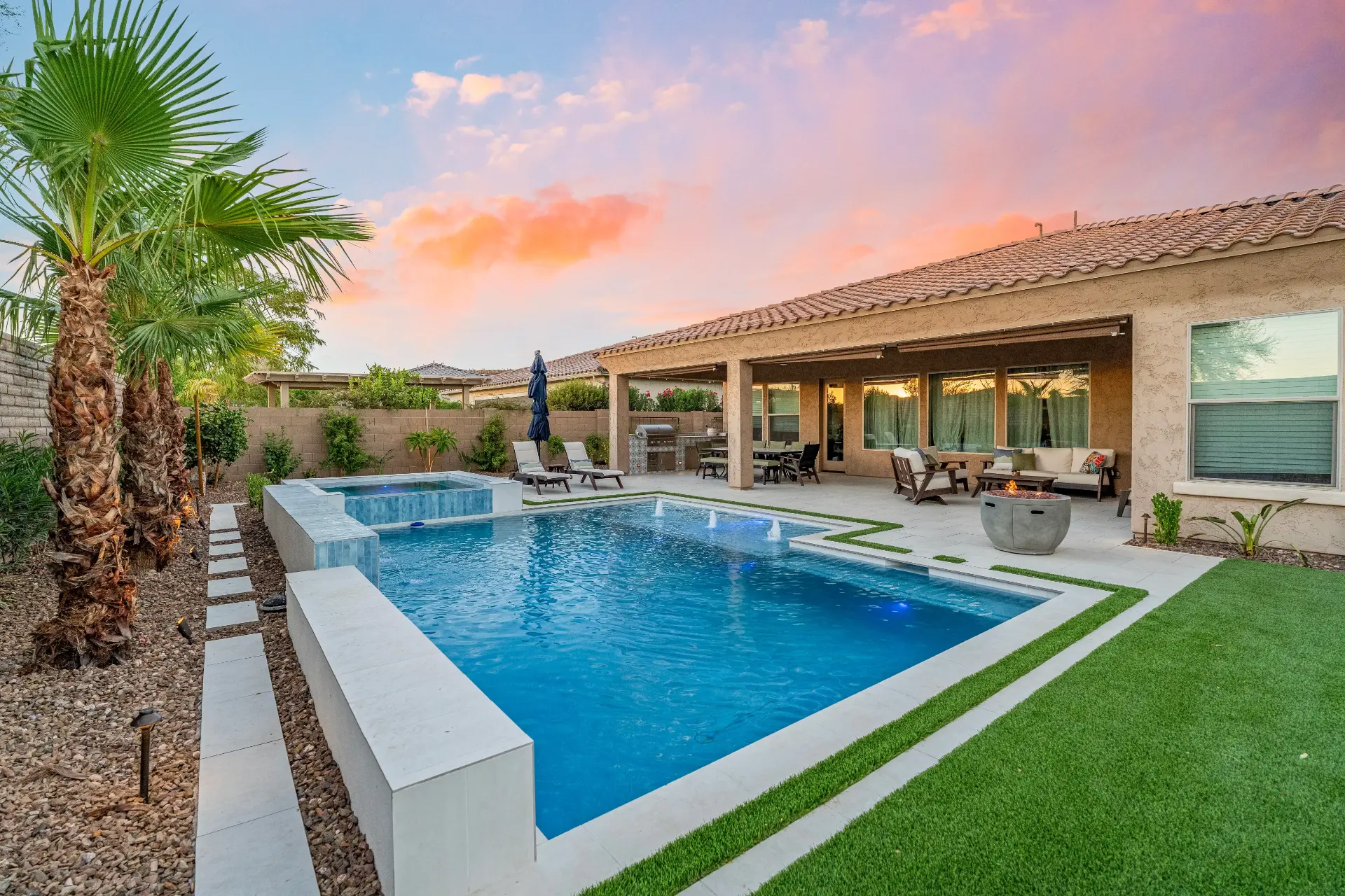 Resort-style pool, spa and covered patio at sunset in an Arizona backyard